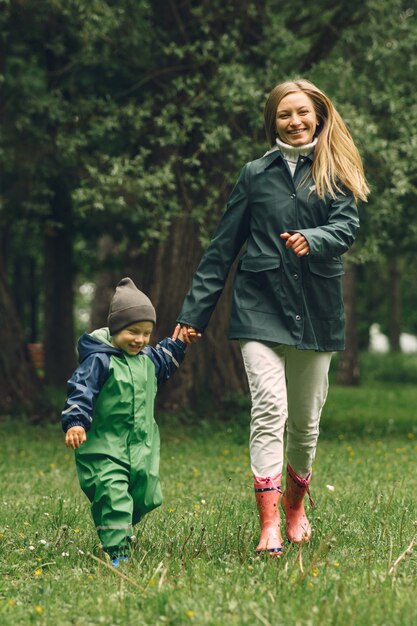 Funny kid in rain boots playing in a rain park