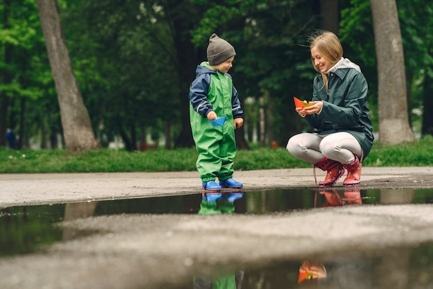 Funny kid in rain boots playing in a rain park