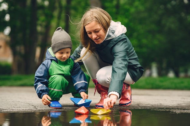 Funny kid in rain boots playing in a rain park