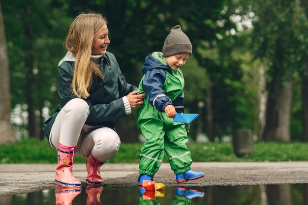 Funny kid in rain boots playing in a rain park