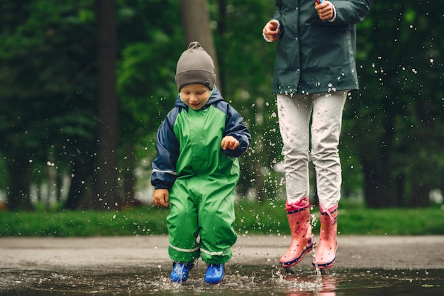 Free photo funny kid in rain boots playing in a rain park