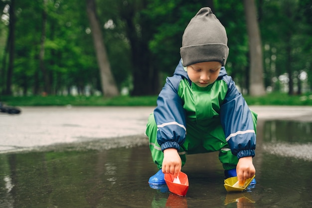 Free photo funny kid in rain boots playing in a rain park