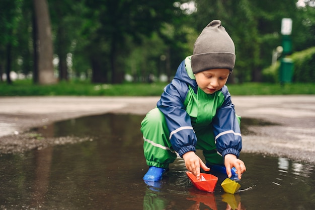 Free photo funny kid in rain boots playing in a rain park