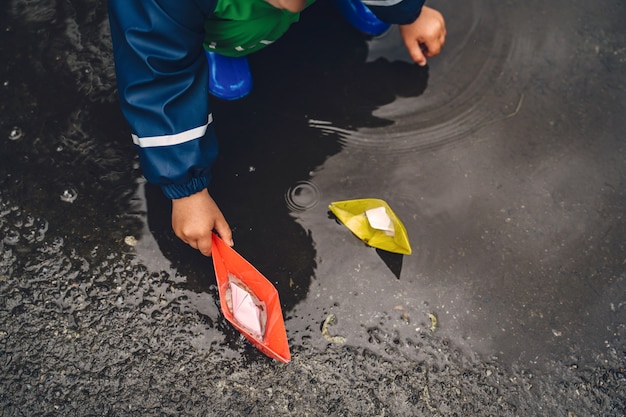 Free Photo funny kid in rain boots playing in a rain park