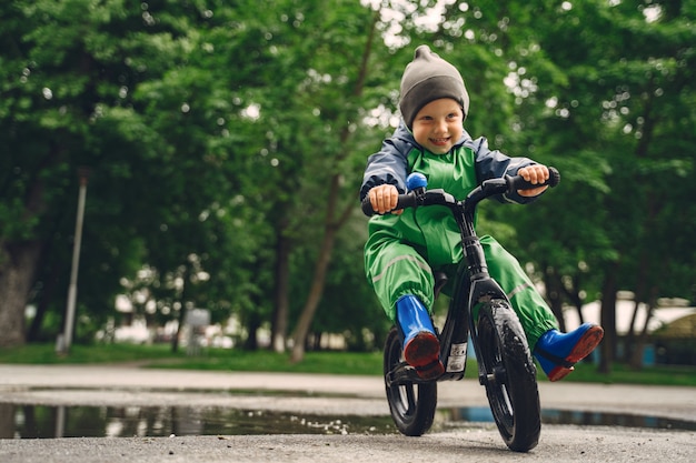 Free photo funny kid in rain boots playing in a rain park