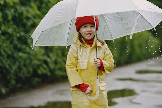 Funny kids in rain boots playing by a puddle