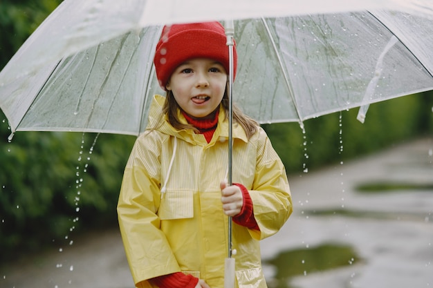 Funny kids in rain boots playing by a puddle