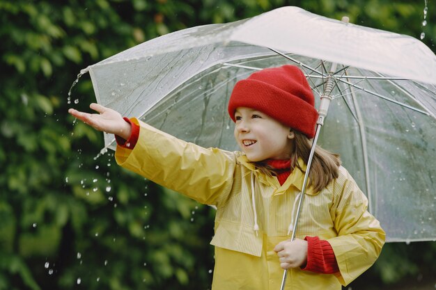 Funny kids in rain boots playing by a puddle