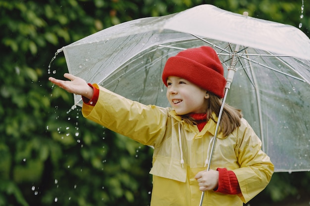 Funny kids in rain boots playing by a puddle