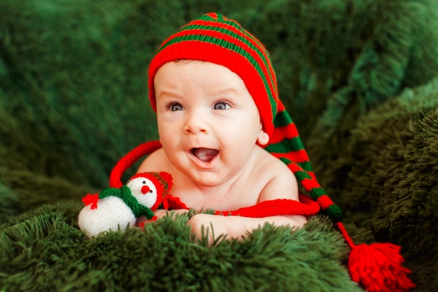 Funny little child in stripped suit lies on soft green armchair 