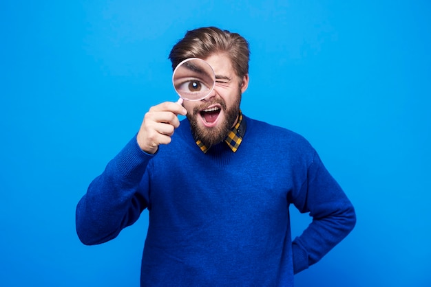 Free photo funny man watching his eyeball in the magnifying glass