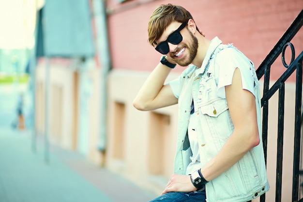 Free photo funny smiling hipster handsome man guy in stylish summer cloth in the street in sunglasses