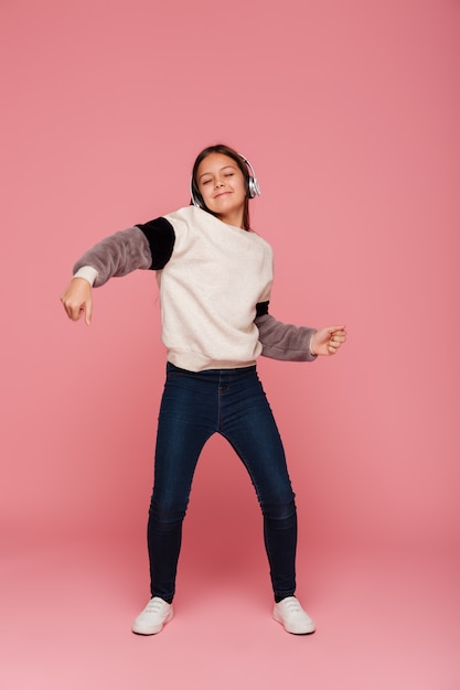 Funny smiling lady dancing while listening music in headphones