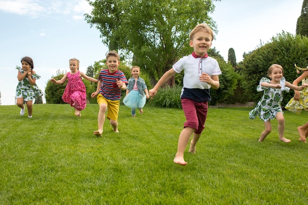 Funny starts. Kids fashion concept. The group of teen boys and girls running at park.