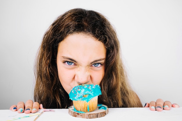 Funny teenager biting cupcake