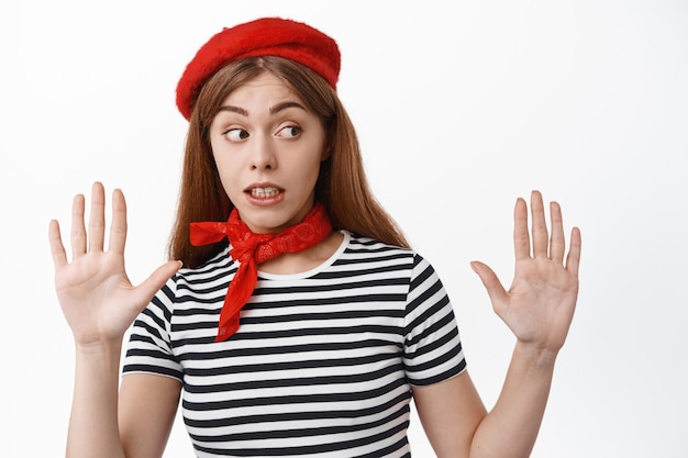 Funny young woman perform pantomime, mime tilting away, raising hands as if leaning on invisible wall, standing over white wall