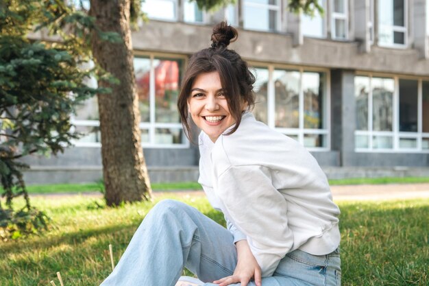 Funny young woman with a bun on her head in a city park