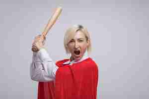 Free photo furious middle-aged blonde superhero woman in red cape raising baseball bat looking at front isolated on white wall with copy space