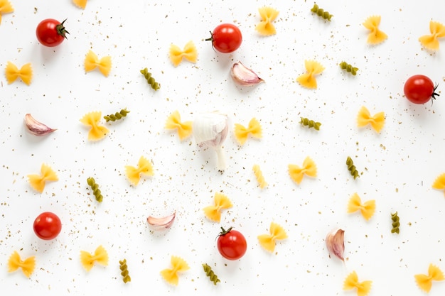 Fusilli and farfalle pasta with ingredient spread on white background