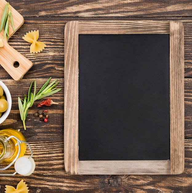 Free photo fusilli with olives and vegetables beside chalkboard