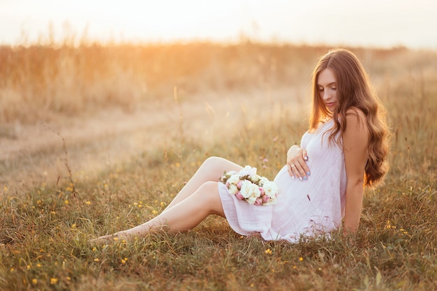 Free photo the future mother sitting on the grass