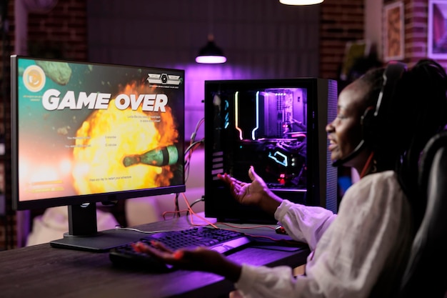 Free photo gamer feeling irked after losing singleplayer action videogame mission, being outsmarted by enemies. african american woman confused after seeing game over screen on gaming computer