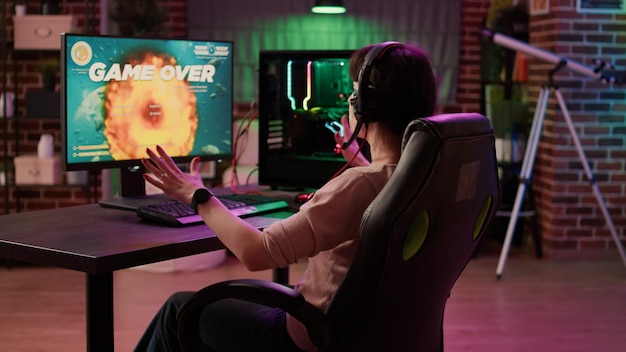 Free photo gamer girl feeling mad shouting at computer screen after losing difficult level in online space shooter on gaming pc. caucasian woman playing multiplayer game disappointed after failing competition.