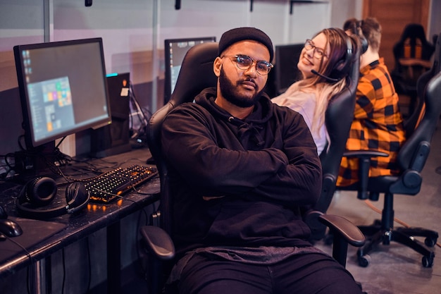 Gamer in glasses is sitting on chair while pretty girl behide his back is smiling to the camera.