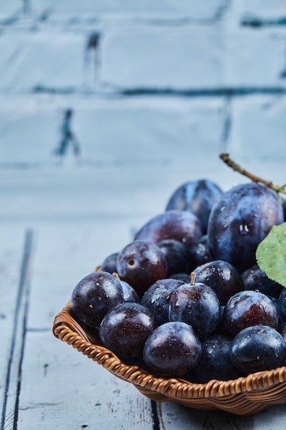 Free photo garden plums in a basket on blue.