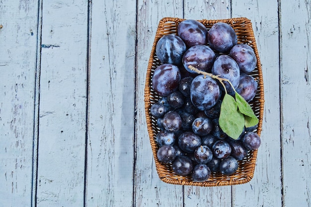 Free Photo garden plums on basket on blue.