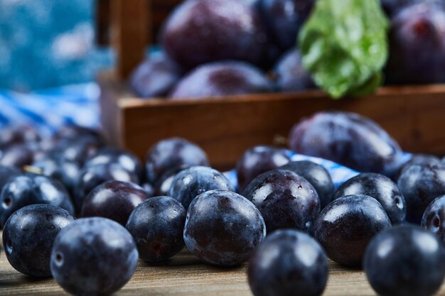 Garden plums scattered through wooden table.