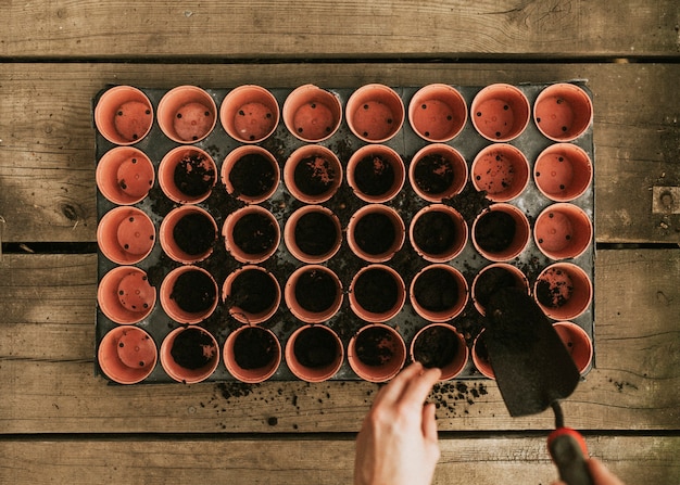 Free Photo gardener adding soil to flower pots flatlay