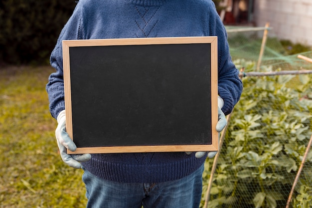 Free photo gardener holding blank blackboard