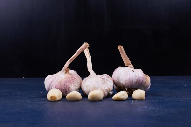 Garlic cloves whole and peeled in the center on black.