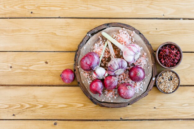 Garlic with red onions, dried barberries, rock salt, quinoa, black pepper flat lay on wooden and cutting board 