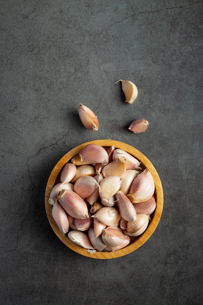 garlics on small wooden plate place on dark floor