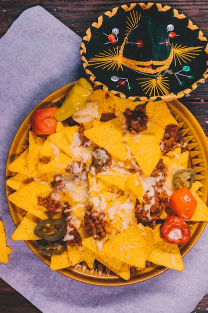 Free photo garnished tasty mexican nachos in plate with mexican hat on table