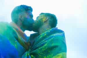 Free photo gay couple kissing soiled paint on gay pride parade