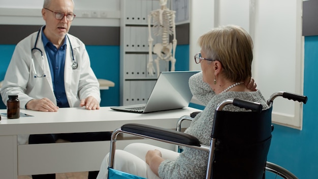 Free photo general practitioner consulting woman with chronic disability in medical office, doing checkup examination with medication. retired patient with impairment and health condition at appointment.