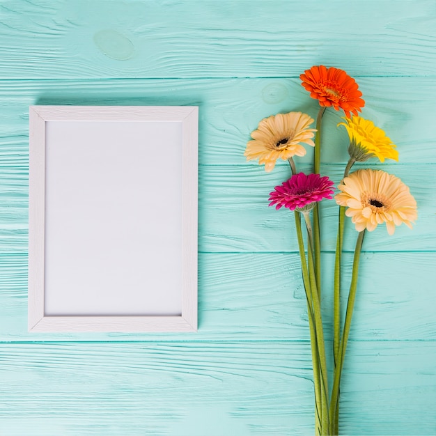 Free photo gerbera flowers with blank frame on table