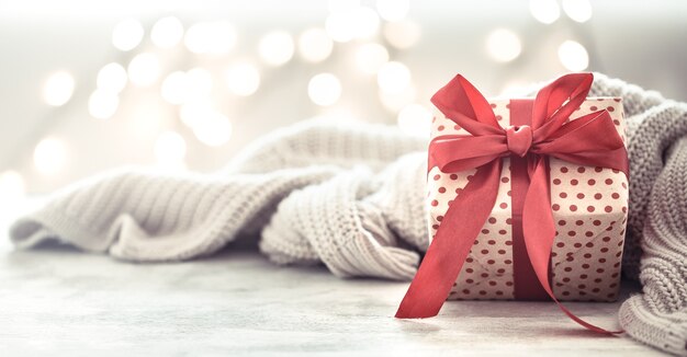 Ggift in a beautiful box with a red bow and grey blanket