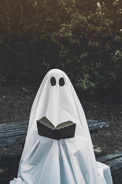 Free photo ghost sitting on bench and reading book