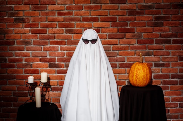 Free Photo ghost in sunglasses posing over brick wall. halloween party.