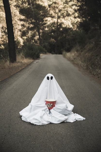 Ghost with popcorn box sitting on countryside road