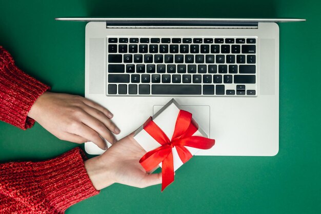 Gift box in female hands and laptop online Christmas shopping concept