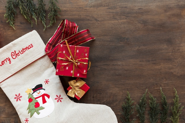 Gift box with Christmas sock on table 