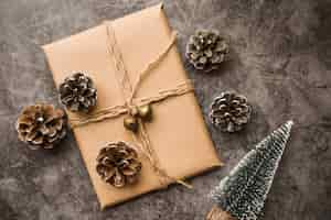 Free photo gift box with cones and small fir trees on table