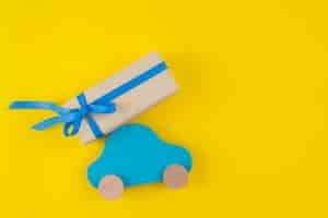 Free photo gift box with toy car on yellow table