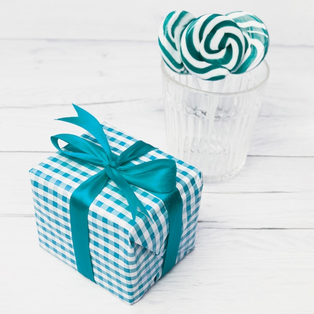 Gift box in wrap near glass with lollipops 