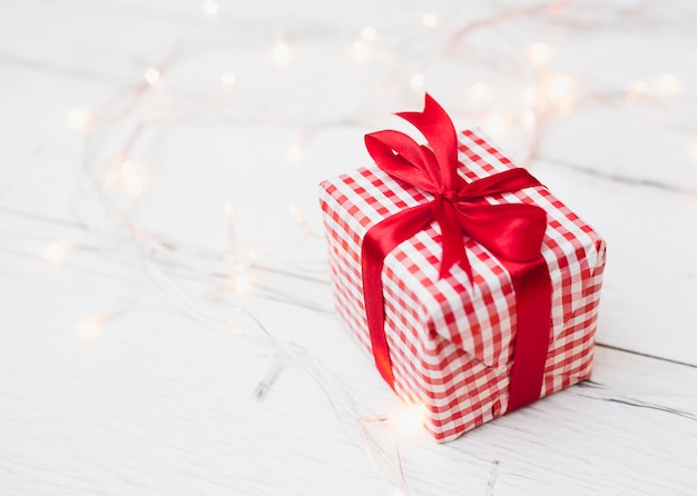 Gift box in wrap near illuminated fairy lights